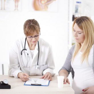 pregnant-patient-looking-at-clipboard-with-doctor